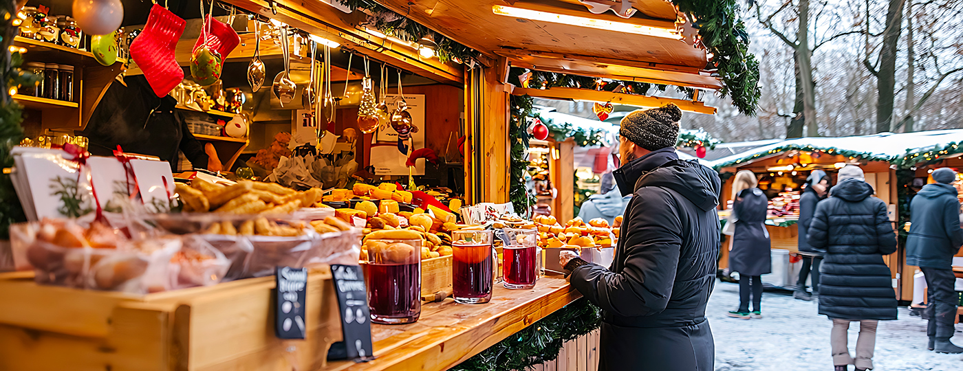 Visitatori a una bancarella natalizia con vin brulè e specialità dell’Alto Adige