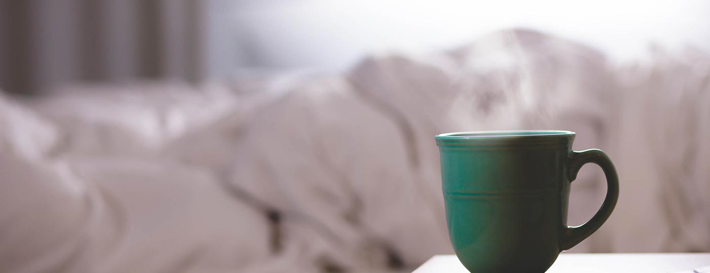 Tazza fumante sul comodino di un hotel